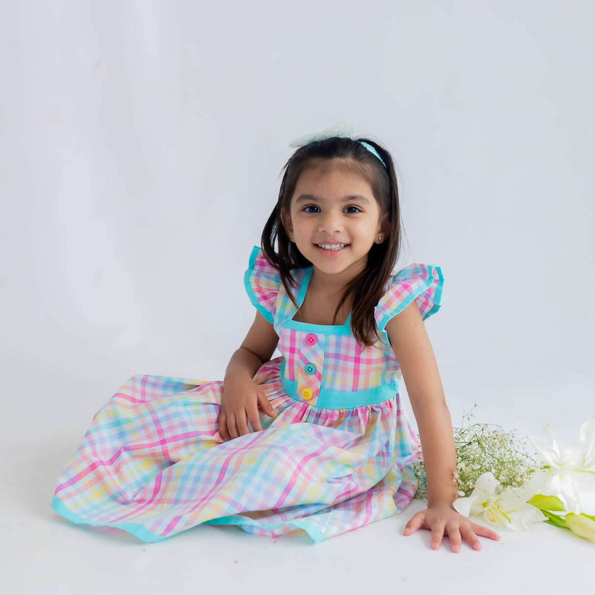 girl sitting down dressed in multicolour plaid dress