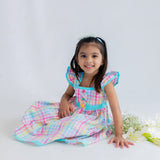 girl sitting down dressed in multicolour plaid dress