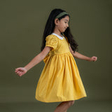 side view of girl twirling in the mustard dot print dress