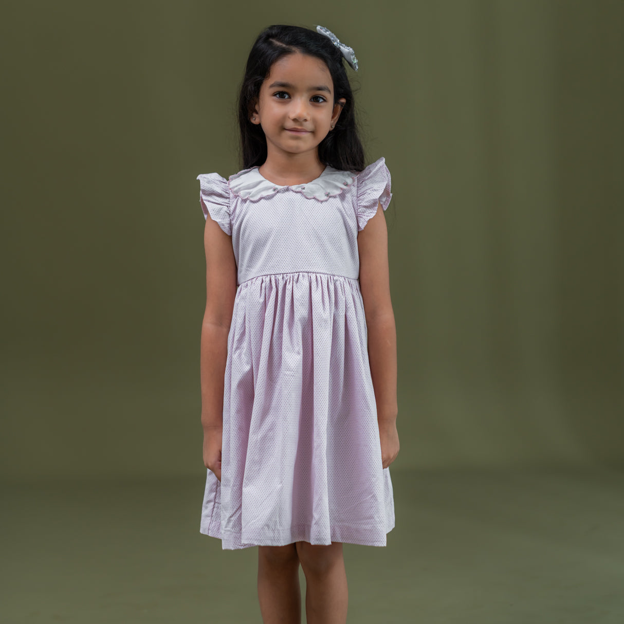 a little girl dressed in pink dot print dress