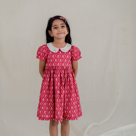 a little girl dressed in red vintage rose print dress with embroidered collar