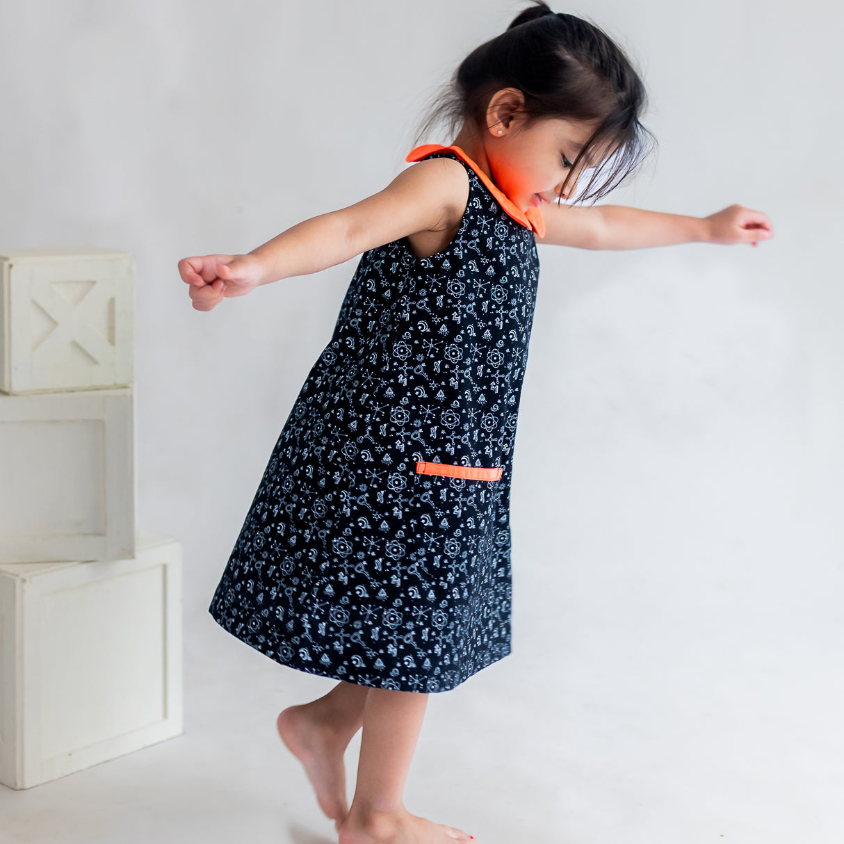 side view of a little girl dressed in  black science print a line dress
