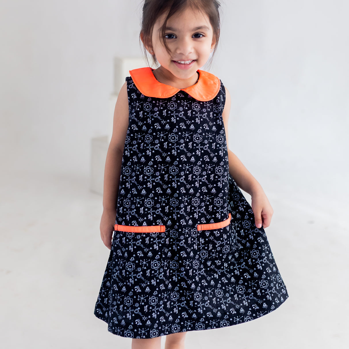 a little girl showing the aline of the  black science print dress