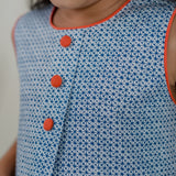 closeup of pleat and orange fabric button detail of the blue print a line dress