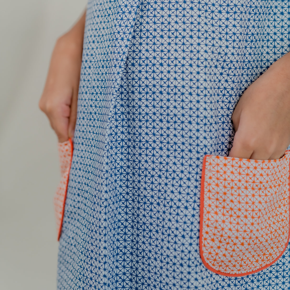 closeup of contrast orange pocket detail of the blue print a line dress