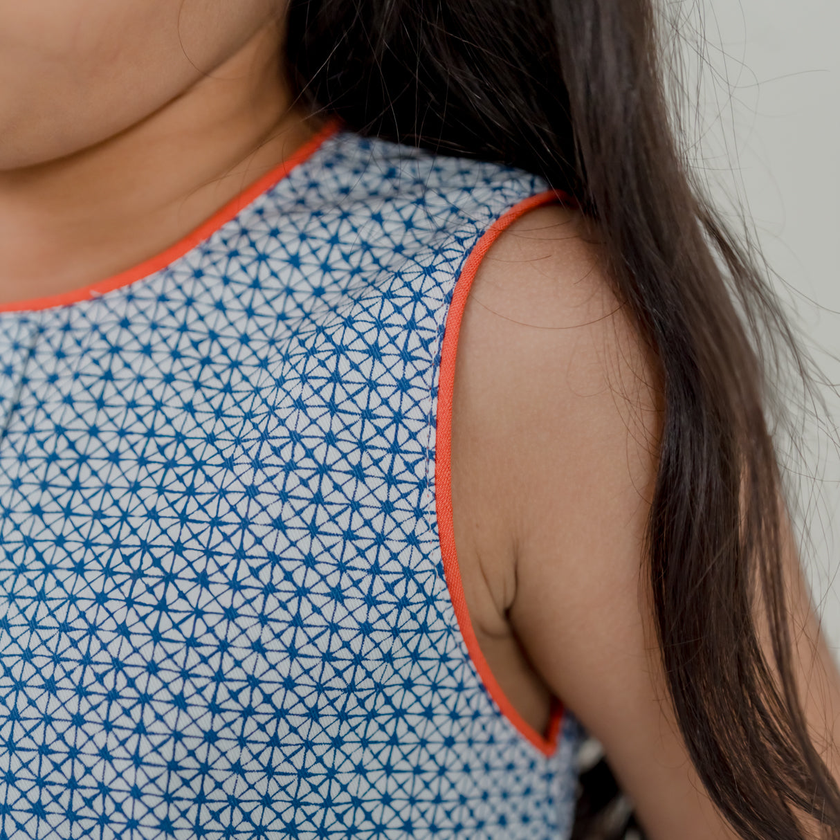 closeup of contrast orange piping detail in the sleeve and neckline of the blue print a line dress