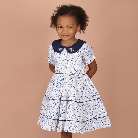 girl wearing white floral hand-embroidered girls dress with navy blue peter pan collar and layered skirt