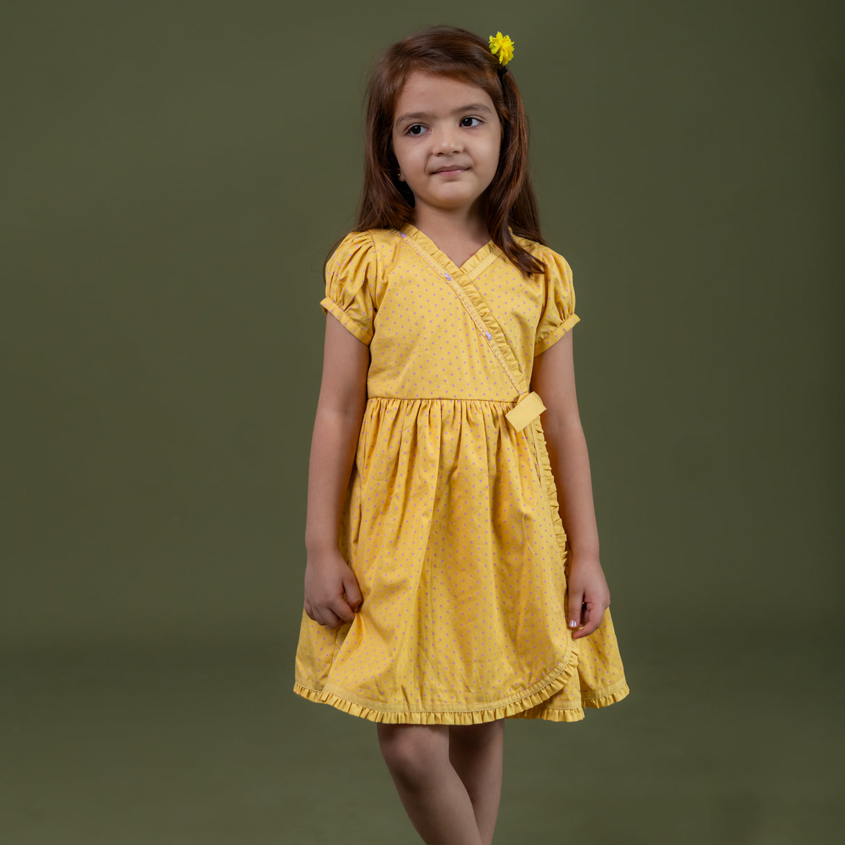 a little girl dressed in mustard crossover dress