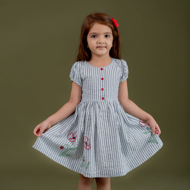 a little girl dressed in blue striped dress with floral embroidery