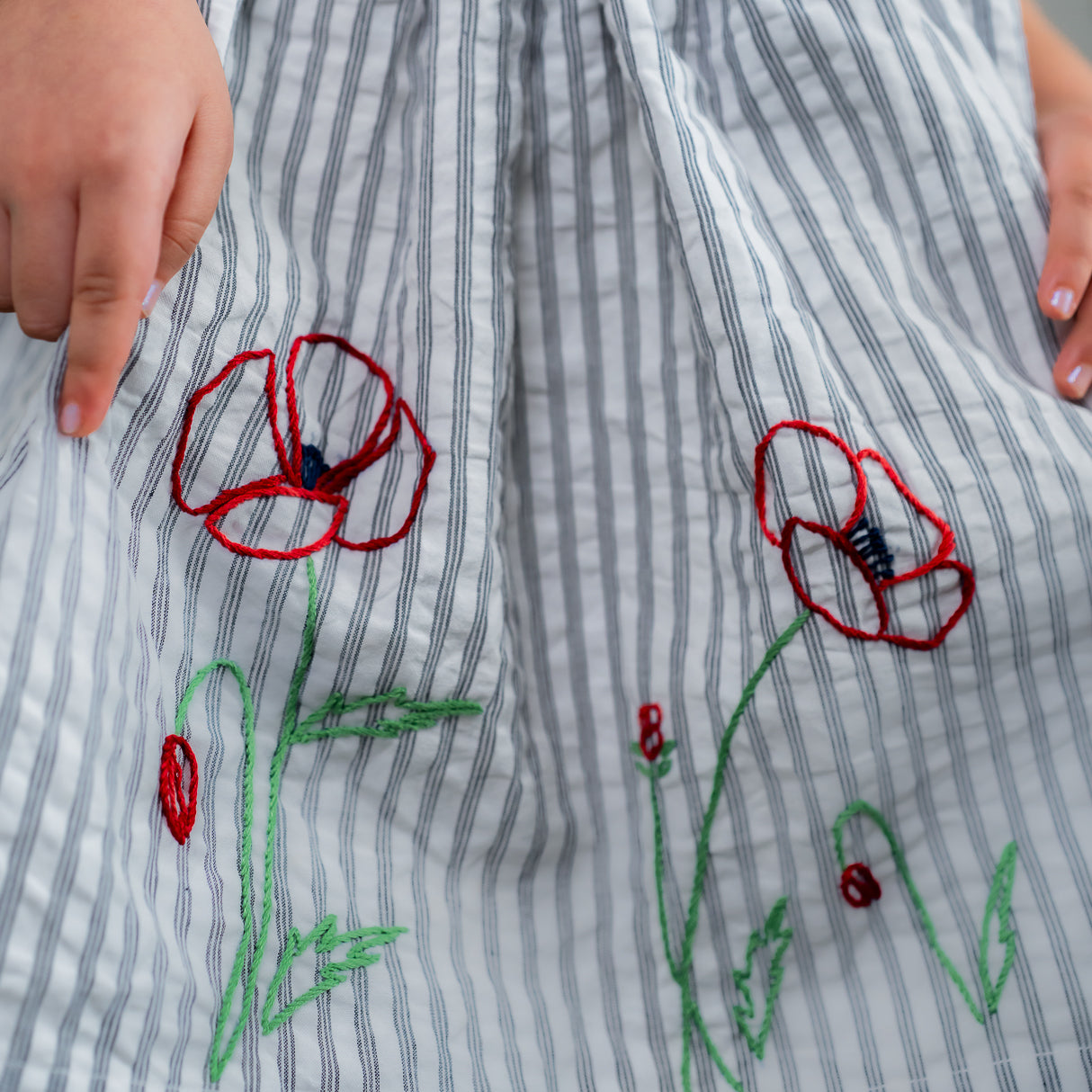 closeup of the embroidery detail in the navy striped dress