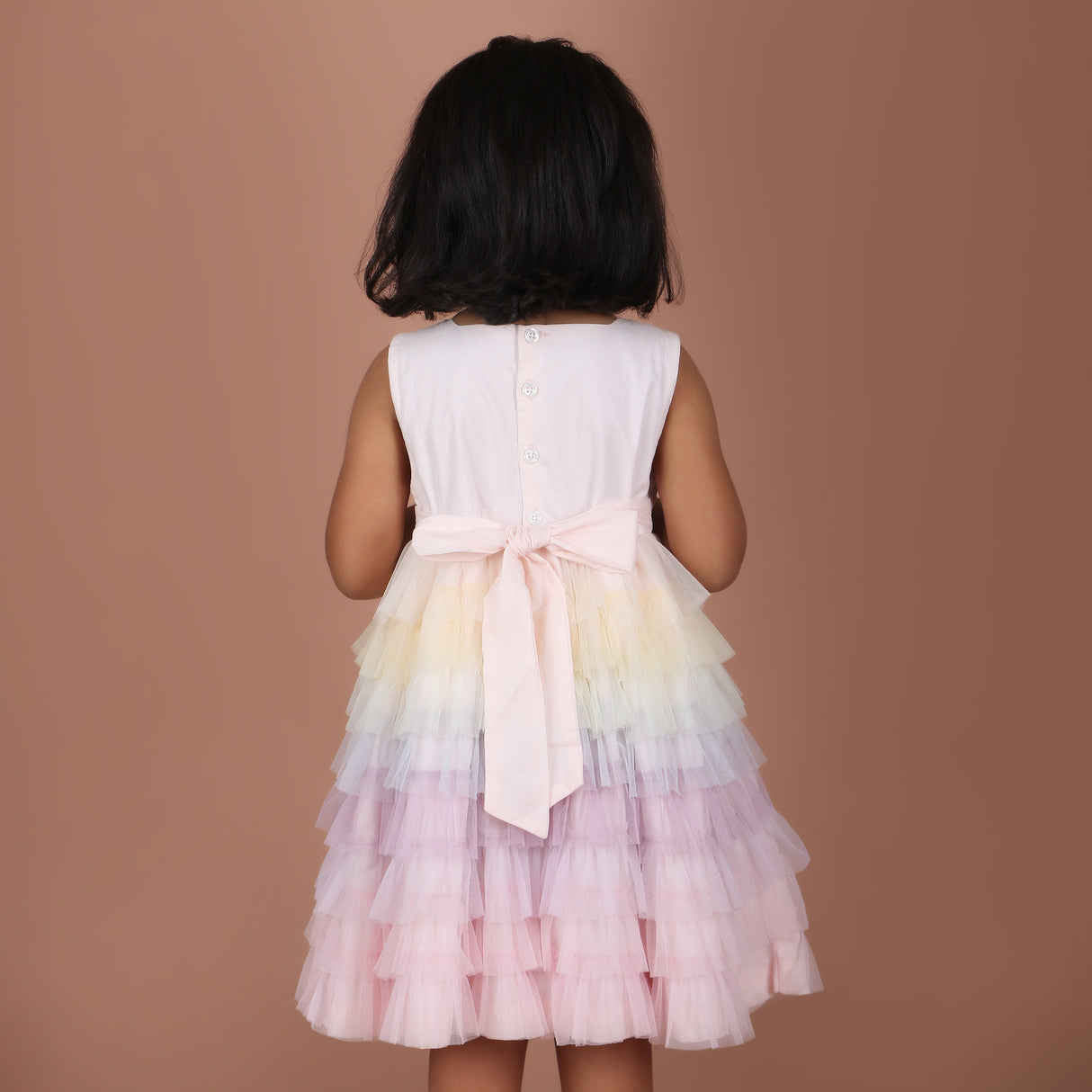 Back view of girls rainbow layered dress with bow tie detail