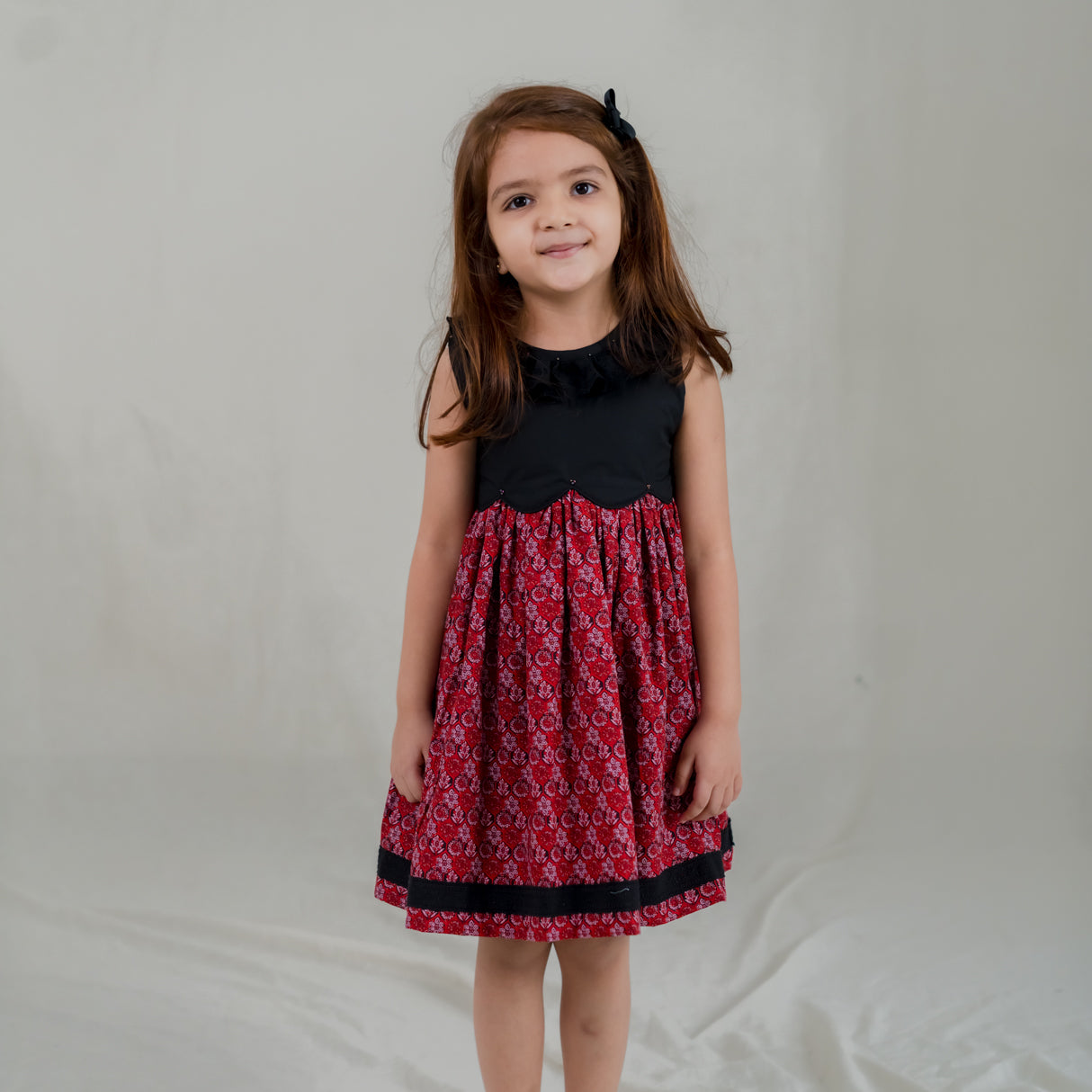 a little girl dressed in black scallop bodice dress