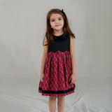 a little girl dressed in black scallop bodice dress