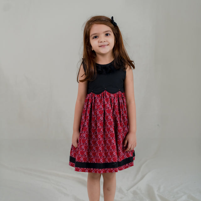 a little girl dressed in black scallop bodice dress