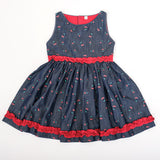 Front view of girls denim cherry print dress with red ruffle detailing