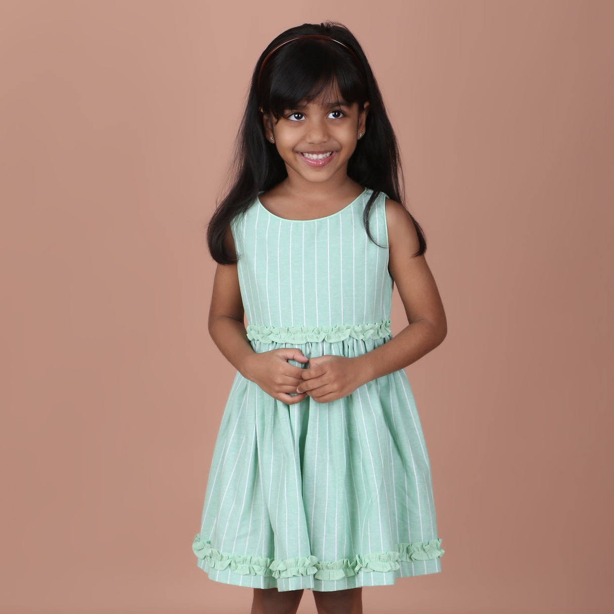 Front view of mint green sleeveless striped dress with ruffle details