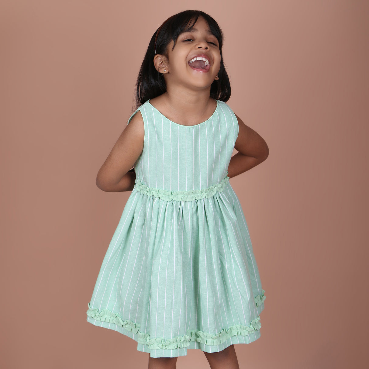 Girl modeling in mint green sleeveless striped dress with flowy gathered skirt