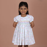 girl wearing white floral dress with rainbow smocking