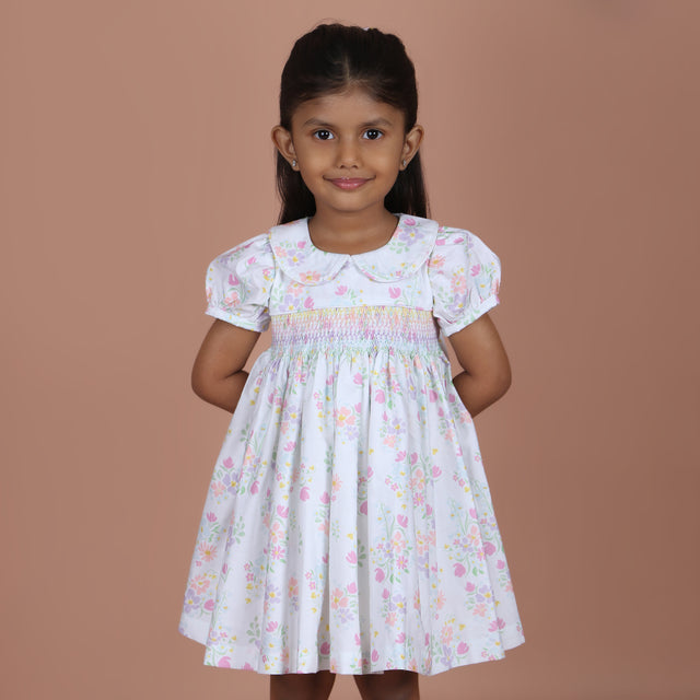 girl wearing white floral dress with rainbow smocking