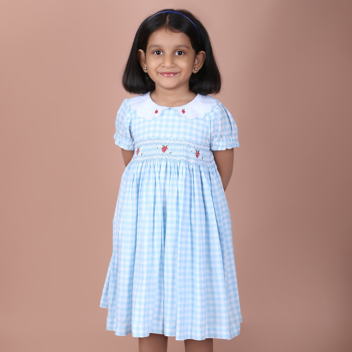 girl wearing royal blue gingham dress with daisy embroidery