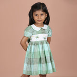 Angled front view of girls green gingham floral embroidered dress
