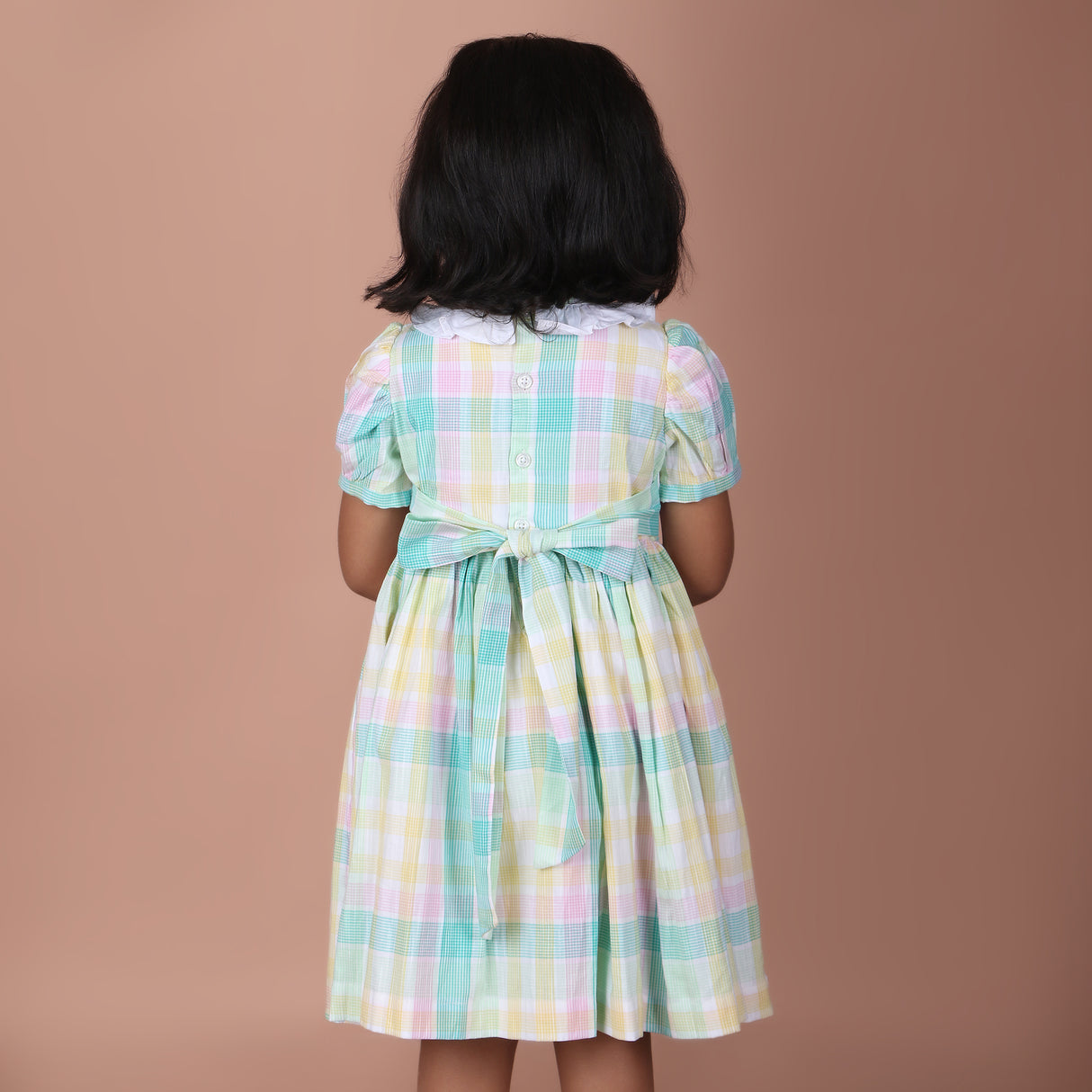 Back view of the pastel plaid smocked dress with back button closure