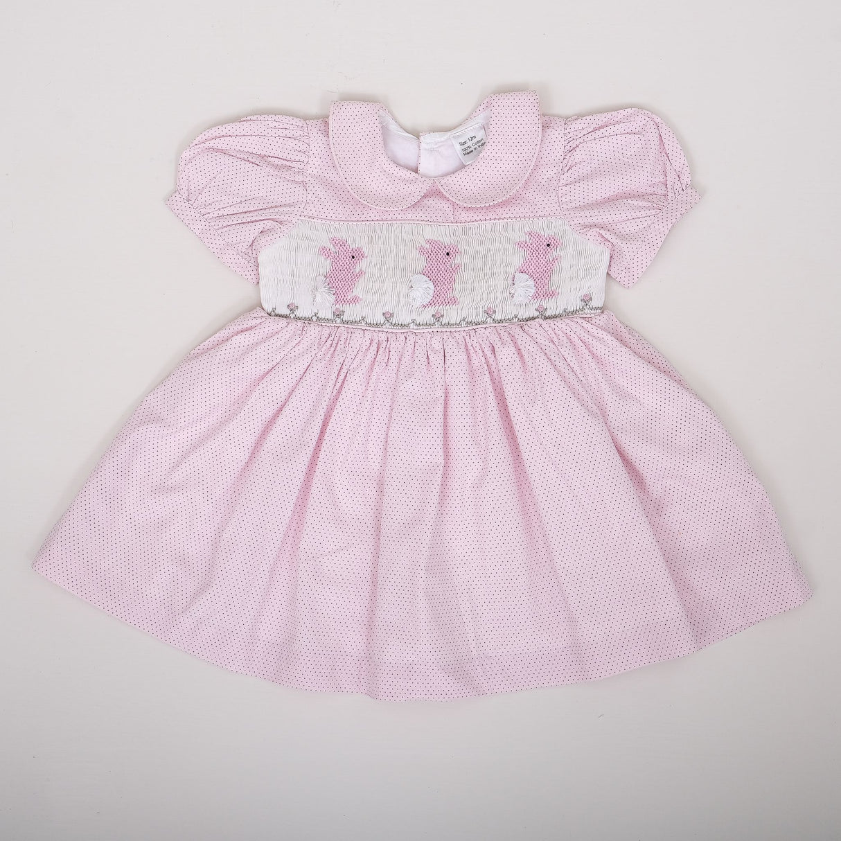 flat lay of pale pink micro dot dress with bunny embroidery