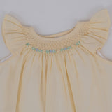 Close-up view of hand smocking and floral embroidery detailing on baby set