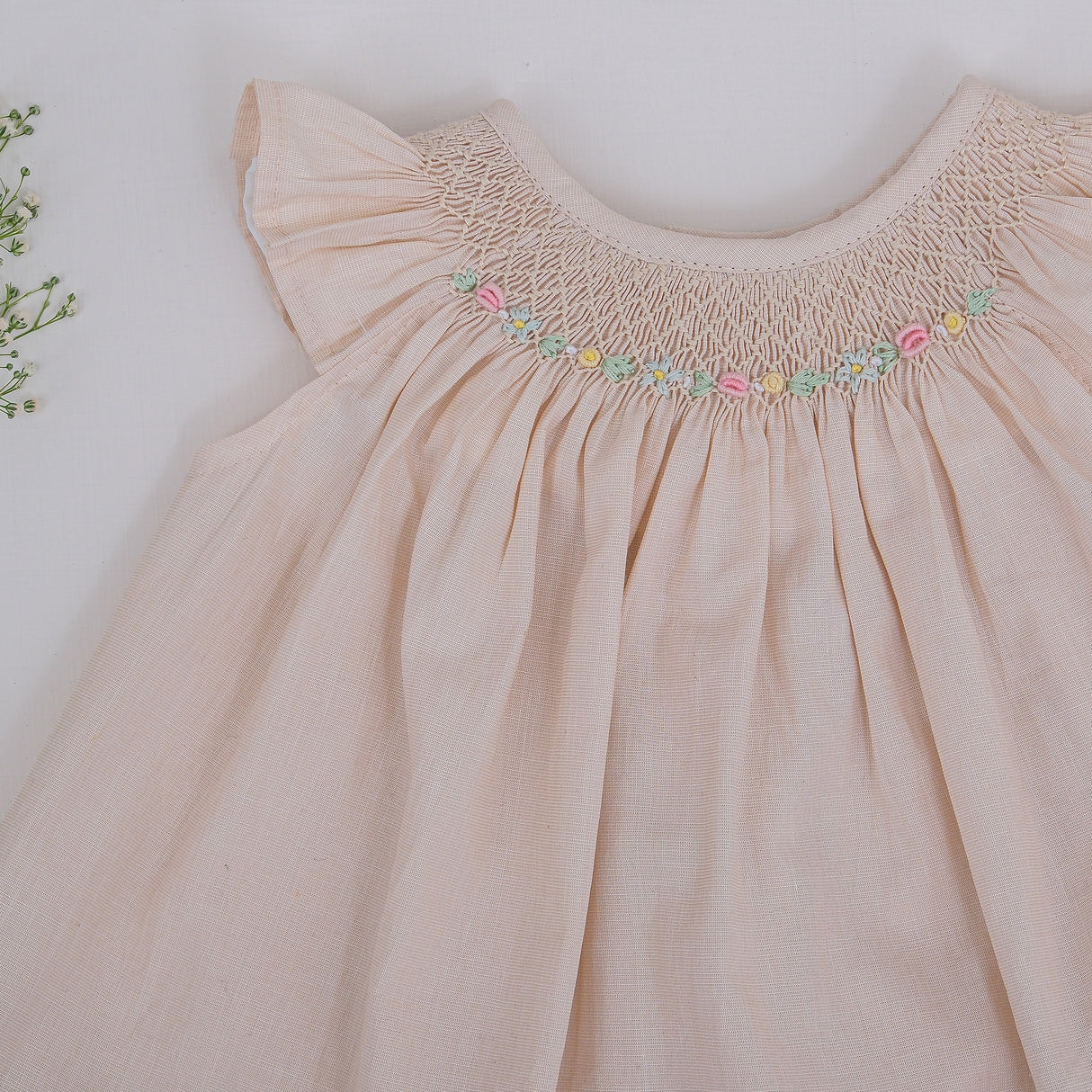 Close-up of hand smocking and colorful embroidery detailing on girls dress