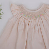 Close-up of hand smocking and colorful embroidery detailing on girls dress