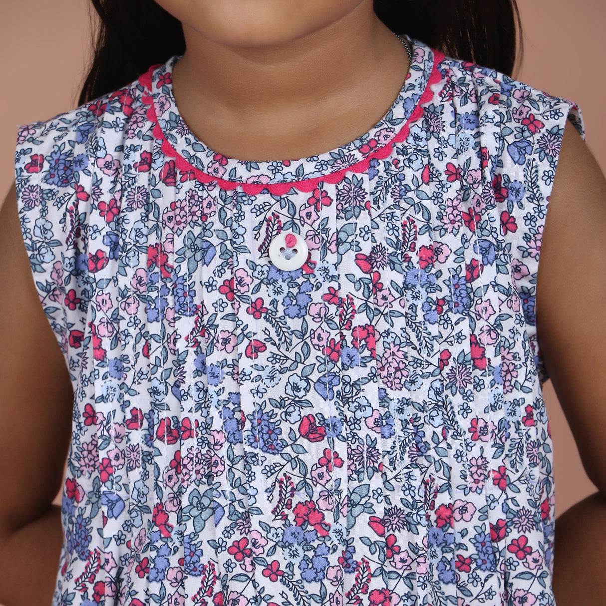 closeup of hand embroidery on button and round neckline with ric rac trim detail