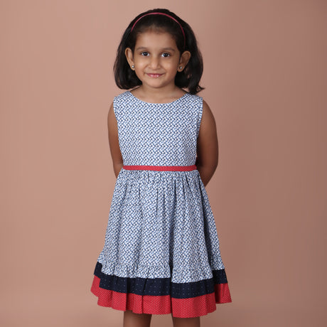front view of girl wearing a navy ditsy floral dress with a red waistband