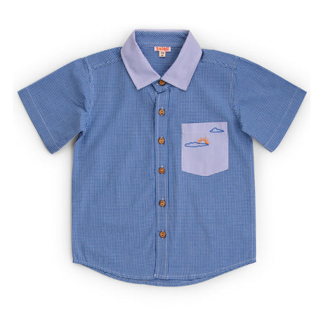 Flatlay of shirt with two closely coordinated fabrics in royal blue with signature sun themed embroidery on pocket