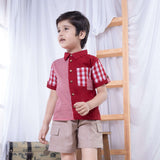 A boy posing in red checked shirt made from a patchwork of big and micro red gingham and solid red voile