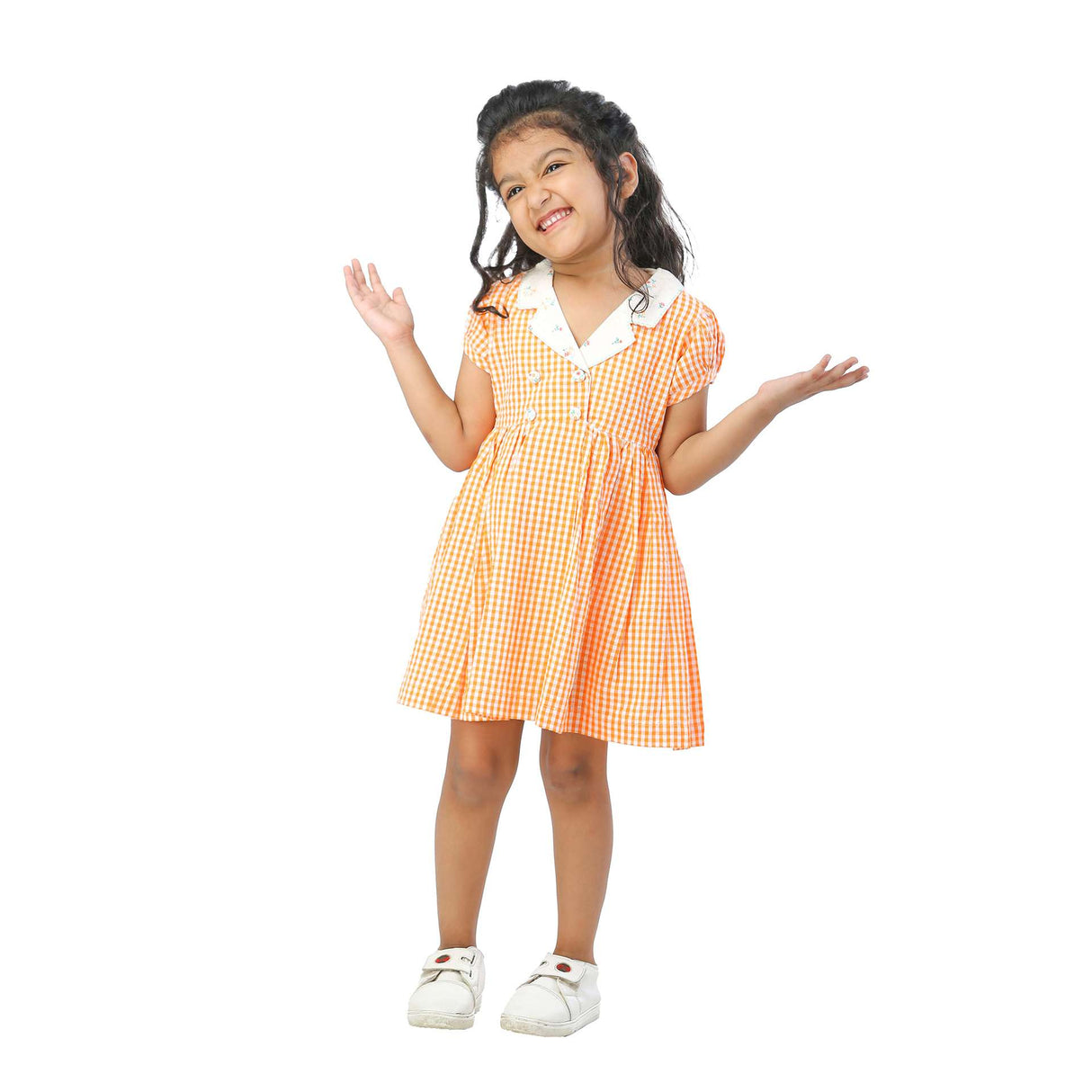 A little girl in orange gingham dress with faux-lapel closure and hand embroidered kantha work on collar