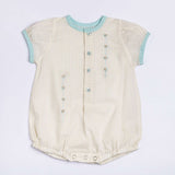 Flatlay of peaches and cream striped hand embroidered onesie for a baby girl