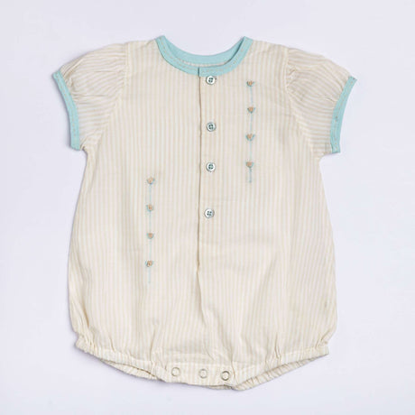 Flatlay of peaches and cream striped hand embroidered onesie for a baby girl