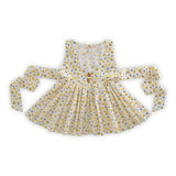 Rear image of floral print overdress with two side slits and wood buttons for front fastening and broad back ties