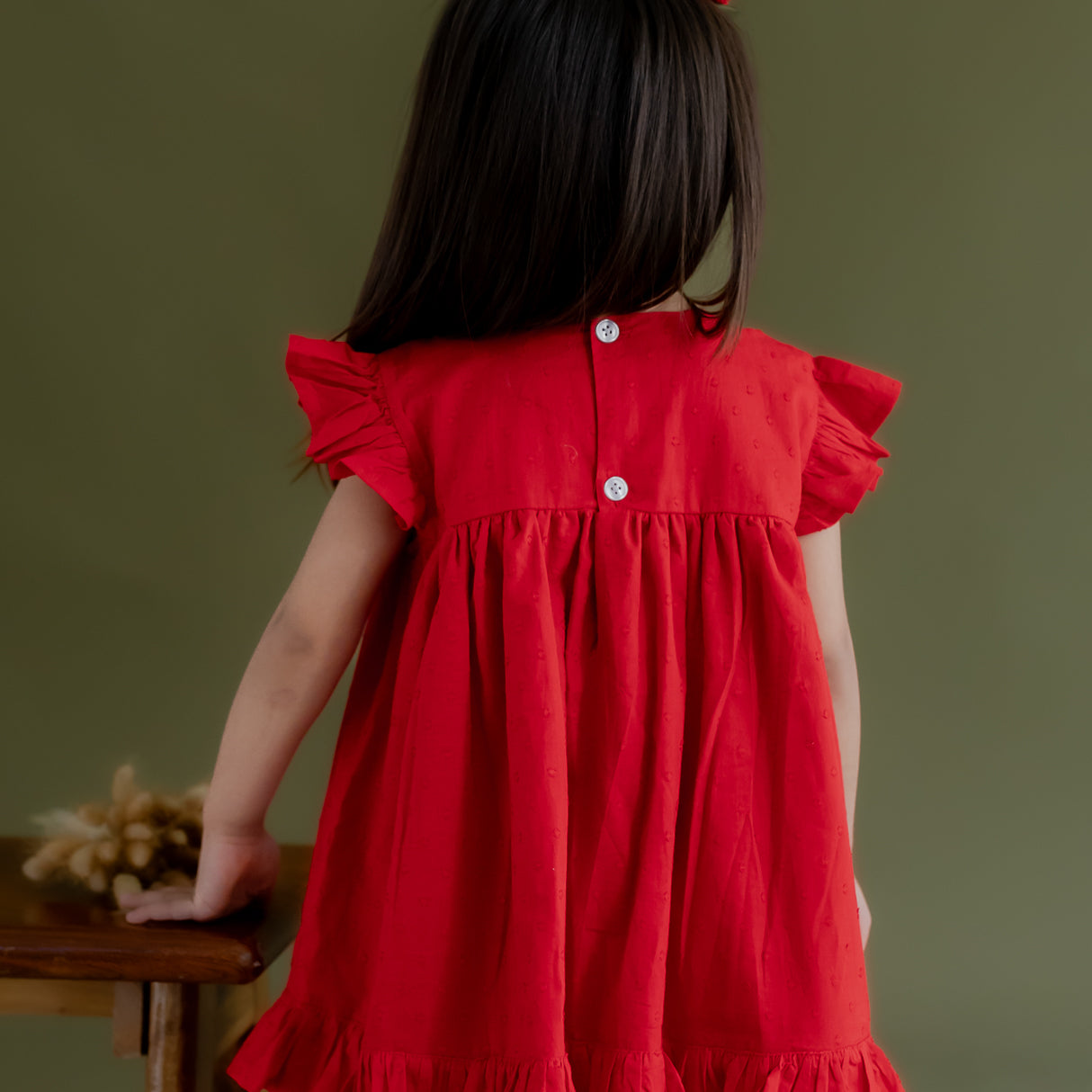 back view of a little girl dressed in red swiss dot dress