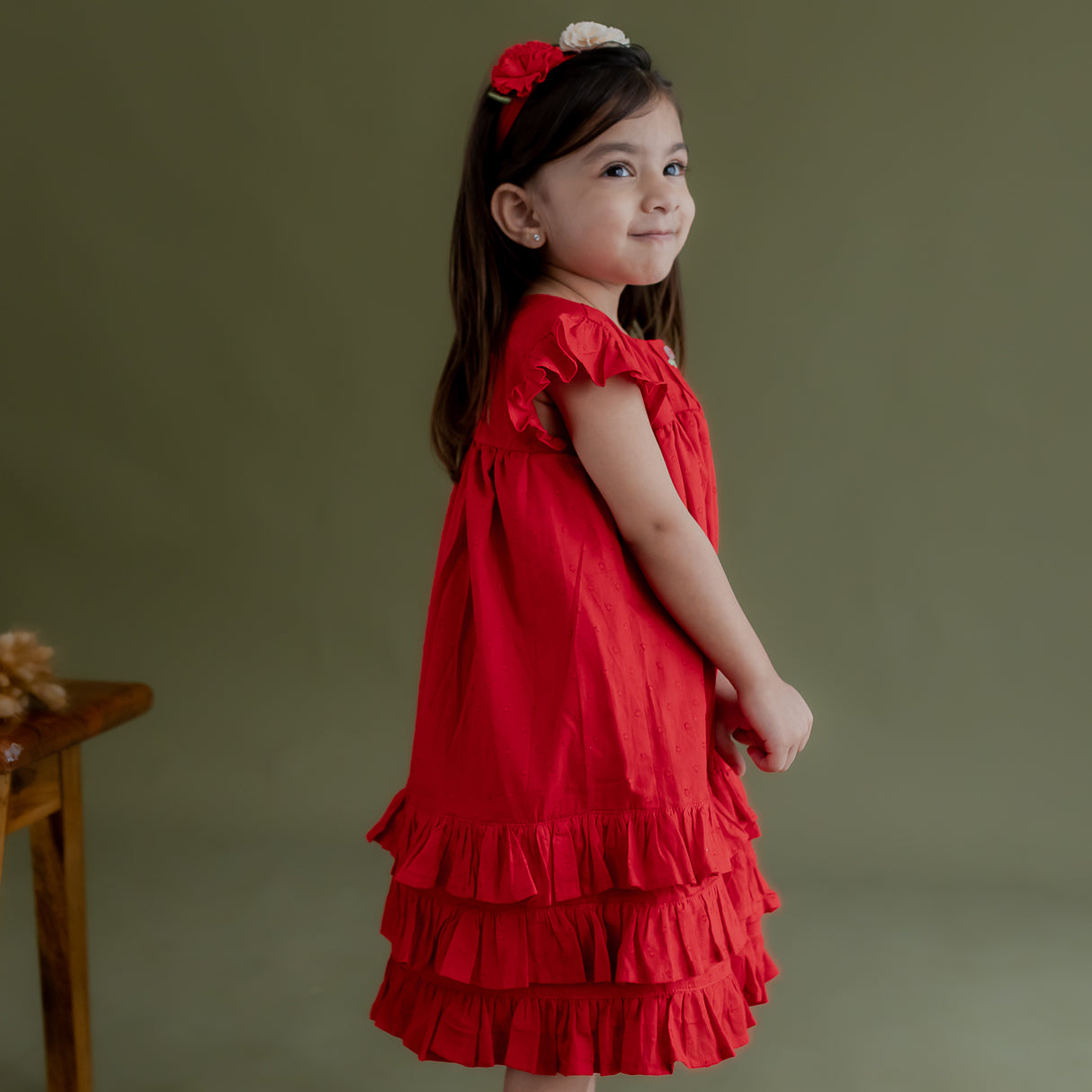 side view of little girl dressed in red swiss dot dress