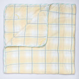 Flatlay of yellow checked blanket with hand embroidered kantha stitching between squares