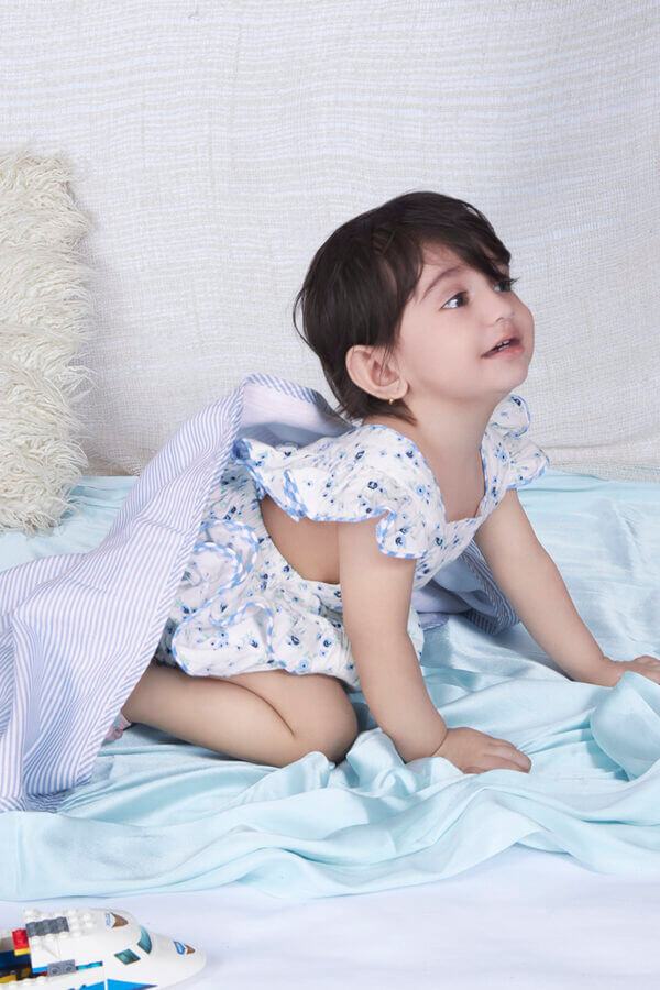 Baby girl in blue ruffle bloomer romper with back crossover straps and ruffles on the bottom