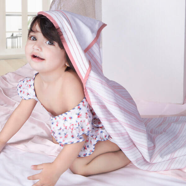 Smiling baby crawls with a hooded coral stripe cotton baby wrap over her head