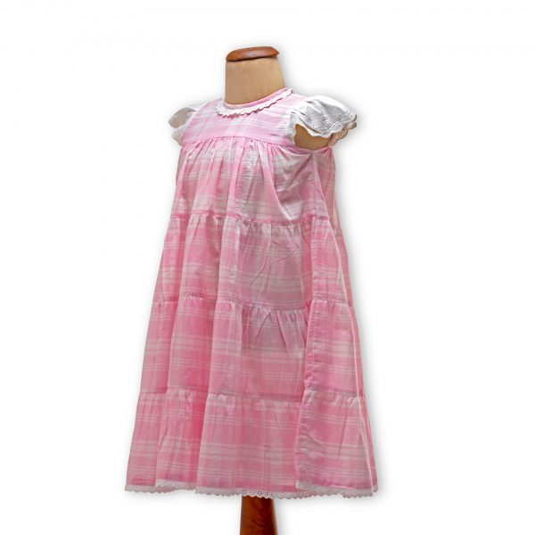 Mannequin with pink plaid gown with an empire waistline and the skirt flowing in gathered tiers with delicate lace trims