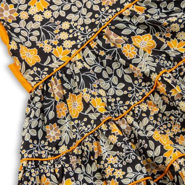 Close up image of black and yellow floral dress with tiered skirt and double back ties