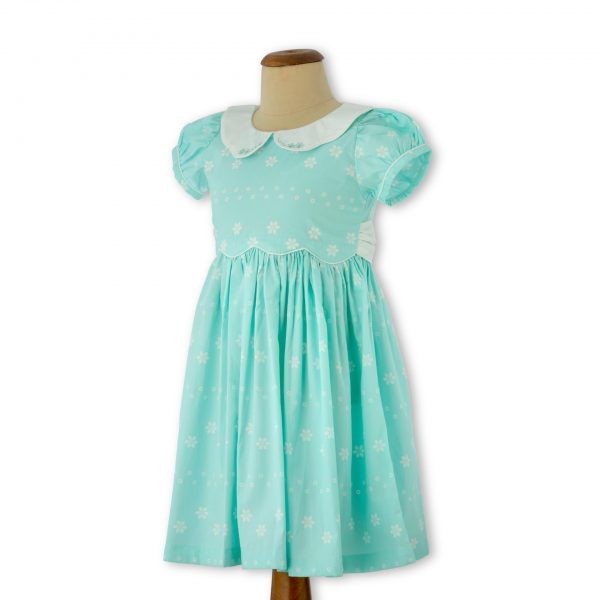 Mannequin image of turquoise blue dress with hand embroidered collar and cuffs with teal cord piping and puff sleeves