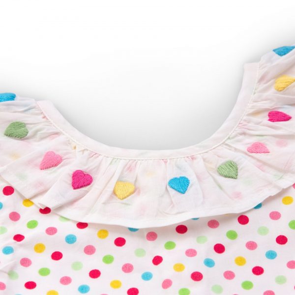 Flatlay of A-line dress in multi colour dot print fabric with white neckline ruffle and colourful heart embroidery on it
