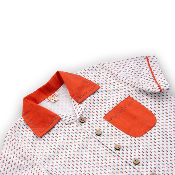 White boys shirt up close, with orange collar and pocket with hand embroidery