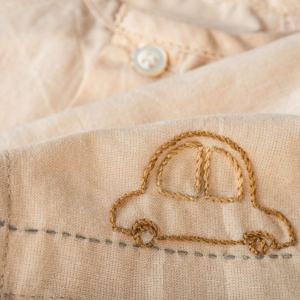 Close up of tan jabla with front buttons and hand embroidered car design