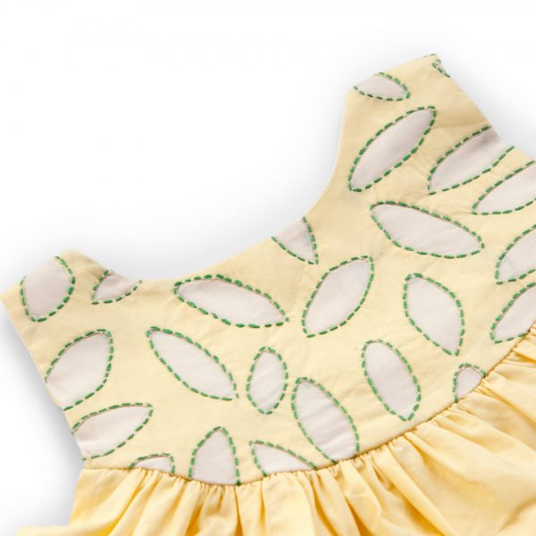 Close-up of hand embroidered applique yoke of yellow cotton dress with a hi lo hem with hand embroidered kantha edging